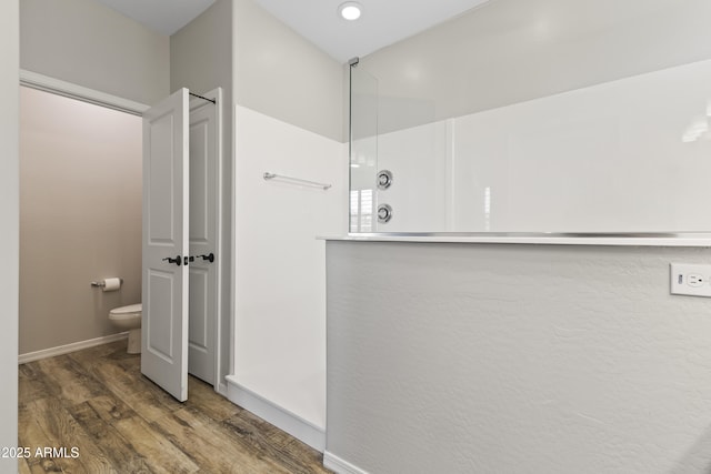 bathroom with wood-type flooring, a shower, and toilet