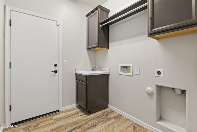 clothes washing area featuring sink, cabinets, light hardwood / wood-style floors, hookup for a washing machine, and hookup for an electric dryer