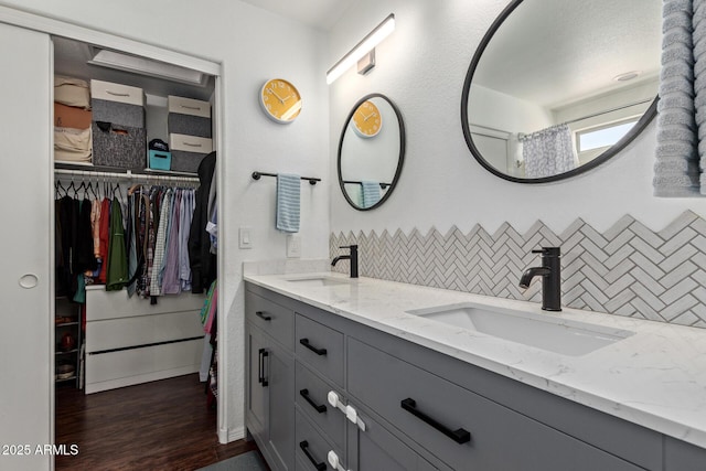3222 E Cortez St, Phoenix, AZ 85028 - bathroom featuring decorative backsplash, double vanity, a spacious closet, wood finished floors, and baseboards