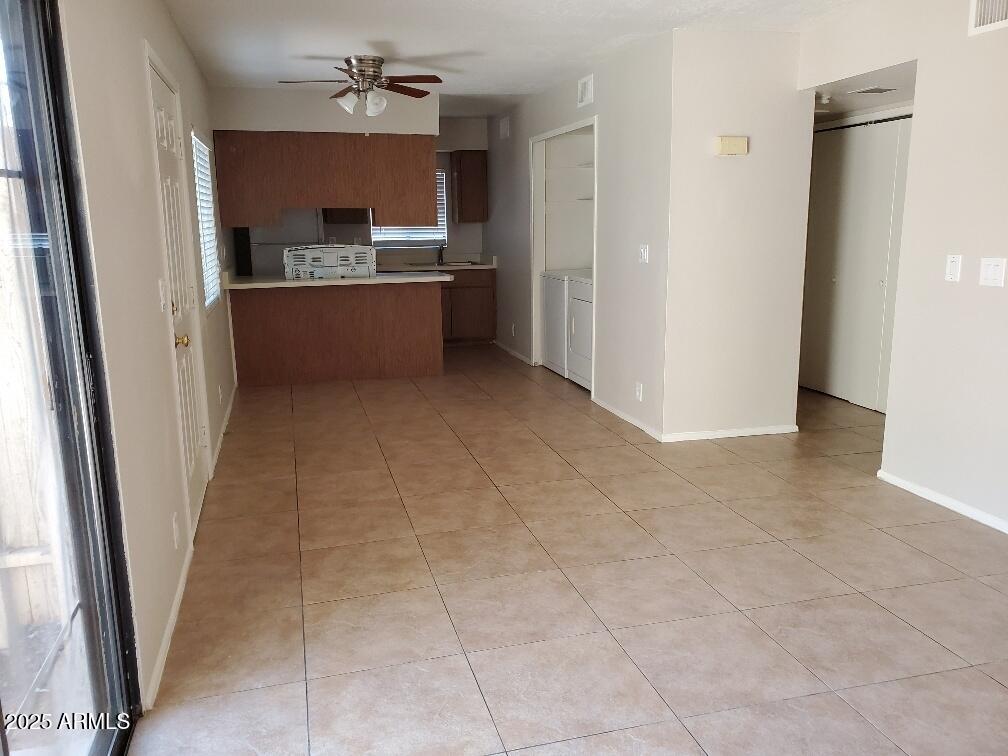 kitchen featuring ceiling fan, washing machine and clothes dryer, kitchen peninsula, and light tile patterned flooring