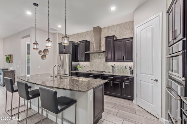 4876 N 207th Ln, Buckeye, AZ 85396 - kitchen with recessed lighting, wall chimney exhaust hood, a kitchen bar, dark stone counters, and appliances with stainless steel finishes