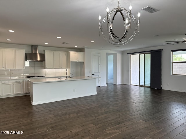 6947 W Spur Dr, Peoria, AZ 85383 - kitchen featuring wall chimney range hood, open floor plan, cooktop, dark wood finished floors, and a kitchen island with sink