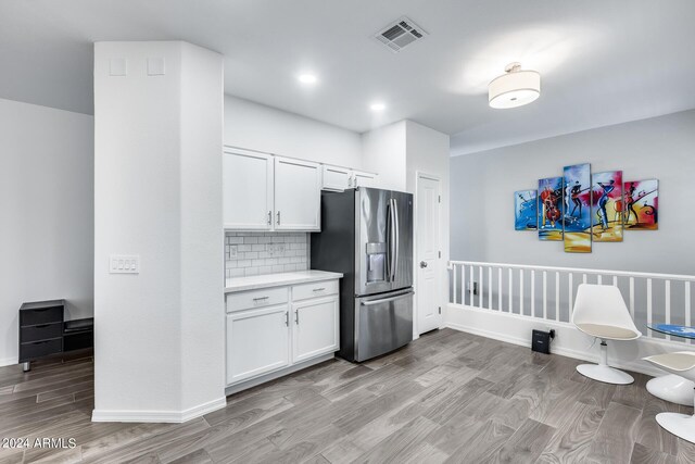 kitchen with light hardwood / wood-style flooring, tasteful backsplash, white cabinetry, and stainless steel refrigerator with ice dispenser