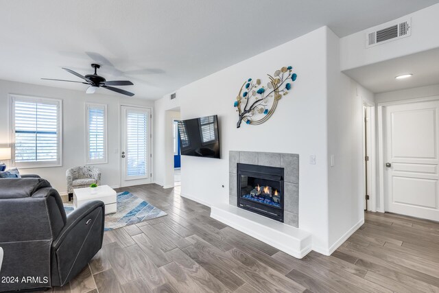 living room featuring a tiled fireplace, hardwood / wood-style flooring, and ceiling fan