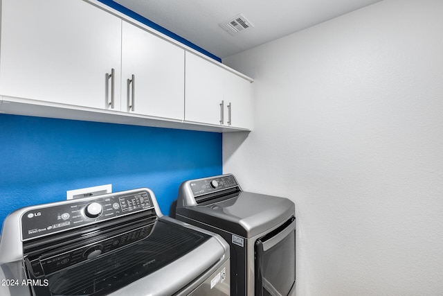 clothes washing area featuring cabinets and separate washer and dryer