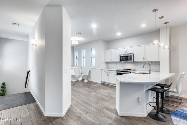 kitchen featuring light hardwood / wood-style flooring, stainless steel appliances, decorative light fixtures, sink, and white cabinets