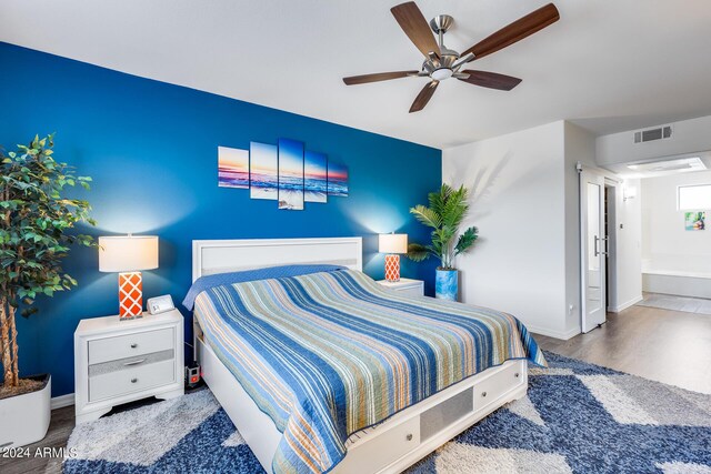 bedroom featuring hardwood / wood-style floors, ceiling fan, and ensuite bath