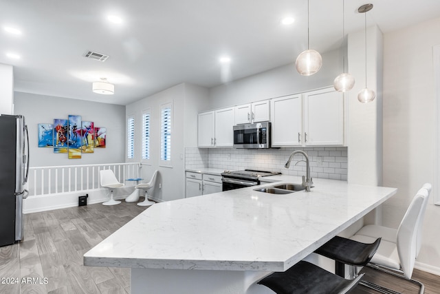 kitchen with pendant lighting, light hardwood / wood-style flooring, stainless steel appliances, sink, and white cabinets