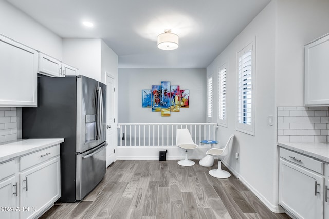 kitchen with tasteful backsplash, light stone counters, light hardwood / wood-style floors, and white cabinetry