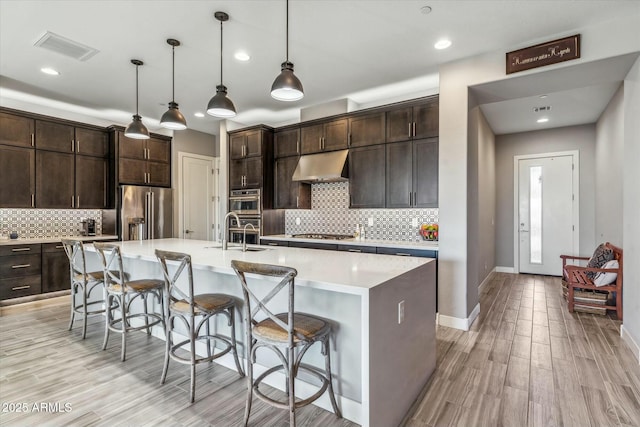 kitchen featuring a large island, sink, appliances with stainless steel finishes, hanging light fixtures, and a kitchen breakfast bar