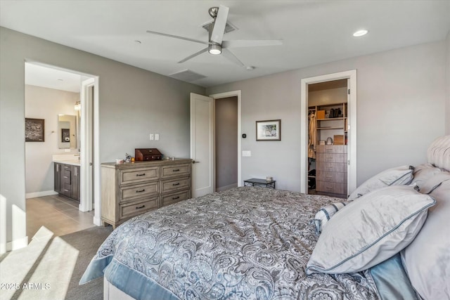 bedroom featuring light tile patterned floors, ceiling fan, connected bathroom, a walk in closet, and a closet