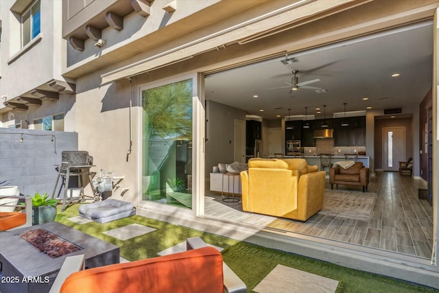 exterior space featuring ceiling fan, a grill, and an outdoor living space with a fire pit