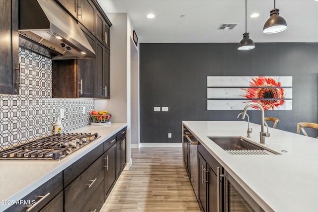 kitchen featuring dark brown cabinets, stainless steel gas stovetop, sink, and hanging light fixtures