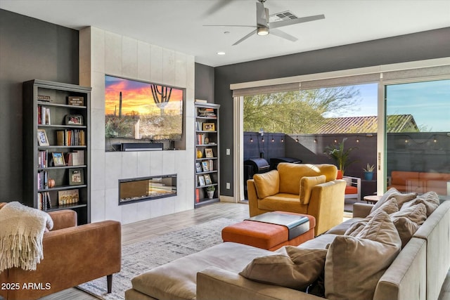 living room featuring ceiling fan, a fireplace, and light hardwood / wood-style flooring