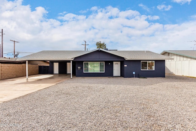 ranch-style home with a carport, fence, driveway, and a shingled roof