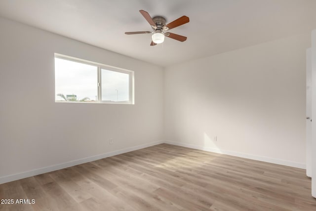 spare room featuring a ceiling fan, light wood-style flooring, and baseboards