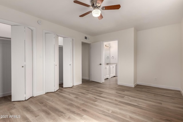 unfurnished bedroom with baseboards, light wood-type flooring, visible vents, and multiple closets