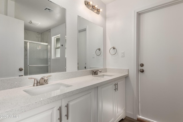 bathroom featuring double vanity, a stall shower, visible vents, and a sink