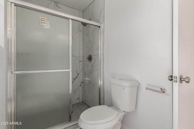 bathroom featuring toilet and a marble finish shower