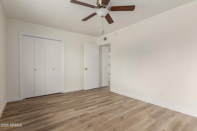 unfurnished bedroom featuring baseboards, visible vents, ceiling fan, wood finished floors, and a closet