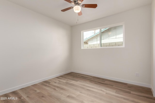 spare room with baseboards, ceiling fan, and light wood finished floors