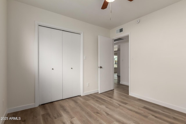 unfurnished bedroom with light wood-style flooring, a ceiling fan, visible vents, baseboards, and a closet