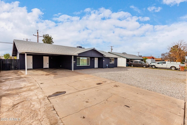 ranch-style house with driveway, a shingled roof, and fence