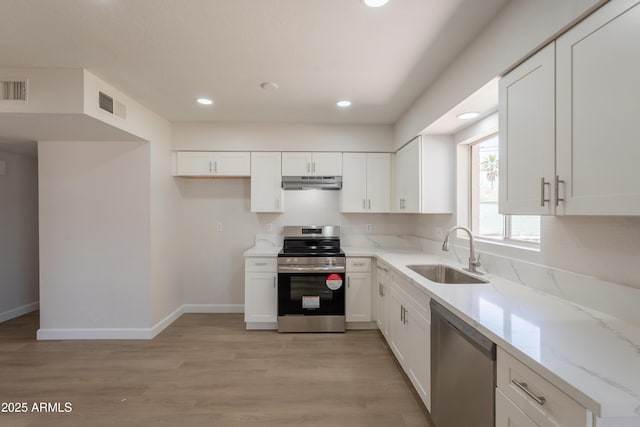 1310 E Ironwood Dr, Buckeye, AZ 85326 - kitchen with appliances with stainless steel finishes, a sink, under cabinet range hood, white cabinets, and light wood-style flooring