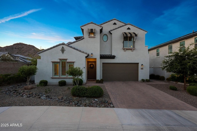 21194 W Hillcrest Blvd, Buckeye, AZ 85396 - mediterranean / spanish-style house with decorative driveway, stucco siding, a garage, a tiled roof, and a balcony