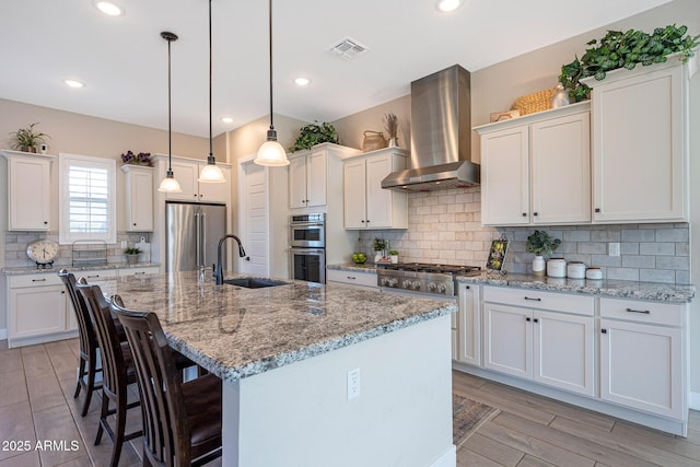 21194 W Hillcrest Blvd, Buckeye, AZ 85396 - kitchen with appliances with stainless steel finishes, wall chimney range hood, a sink, white cabinetry, and a breakfast bar