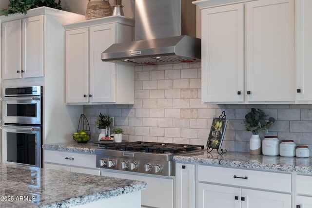21194 W Hillcrest Blvd, Buckeye, AZ 85396 - kitchen with wall chimney range hood, appliances with stainless steel finishes, tasteful backsplash, white cabinets, and light stone countertops