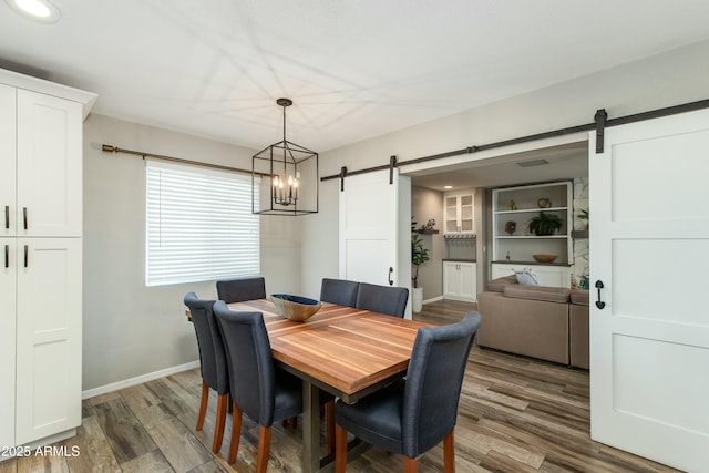 dining area featuring a barn door, wood finished floors, and baseboards