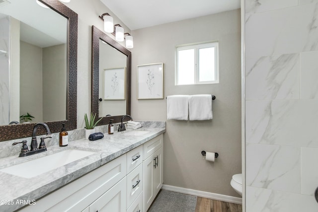 bathroom featuring toilet, a sink, baseboards, and wood finished floors