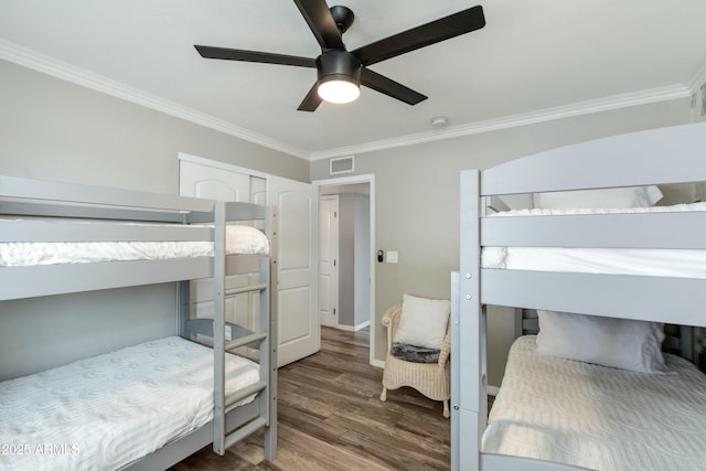 bedroom with ceiling fan, visible vents, wood finished floors, and ornamental molding