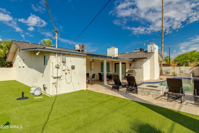 rear view of property featuring a yard, fence, a patio, and stucco siding