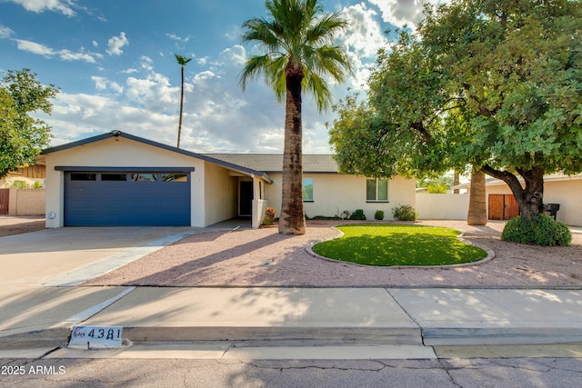 ranch-style house featuring a garage, fence, concrete driveway, and stucco siding