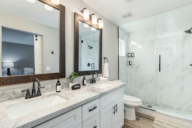 bathroom with visible vents, a sink, a marble finish shower, and wood finished floors