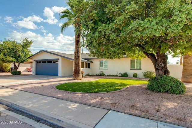 view of front of house with a front yard, driveway, an attached garage, and stucco siding