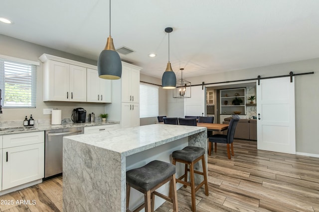 kitchen featuring dishwasher, a barn door, light wood-style flooring, and white cabinetry