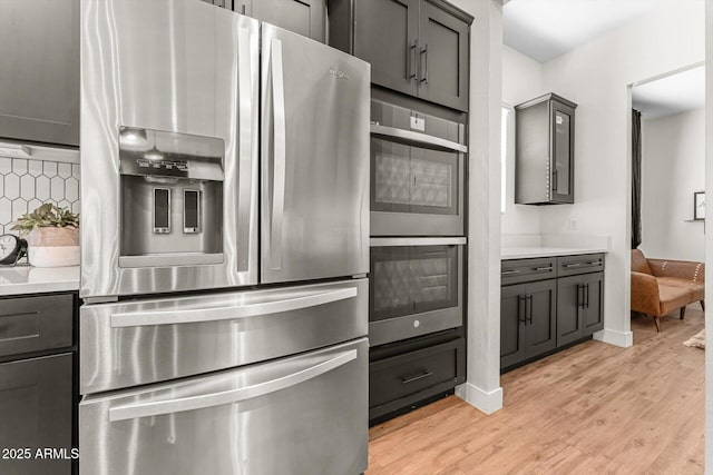 141 S 156th Dr, Goodyear, AZ 85338 - kitchen featuring light countertops, stainless steel appliances, gray cabinets, light wood-style flooring, and decorative backsplash