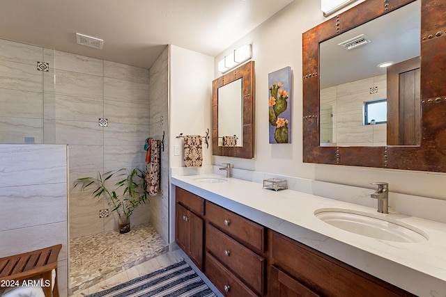 bathroom featuring tile patterned flooring, a tile shower, and vanity