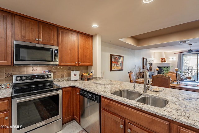 kitchen featuring light stone counters, kitchen peninsula, sink, and appliances with stainless steel finishes