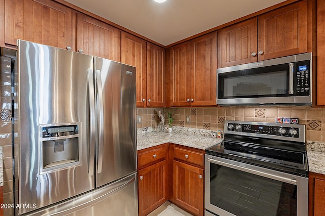 kitchen with light stone counters, appliances with stainless steel finishes, and tasteful backsplash