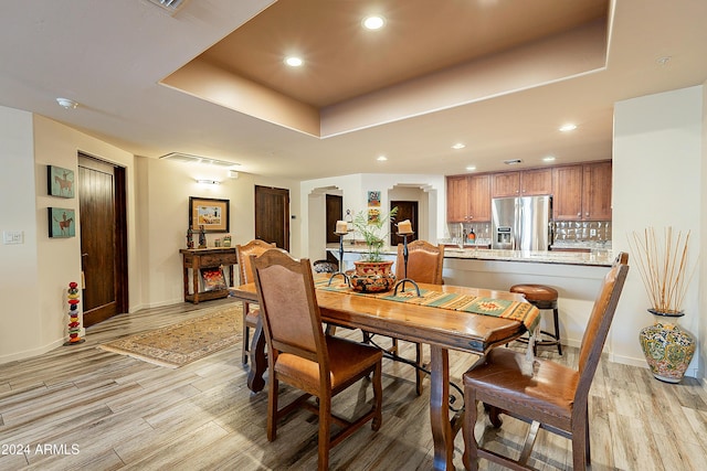 dining space featuring light wood-type flooring and a tray ceiling