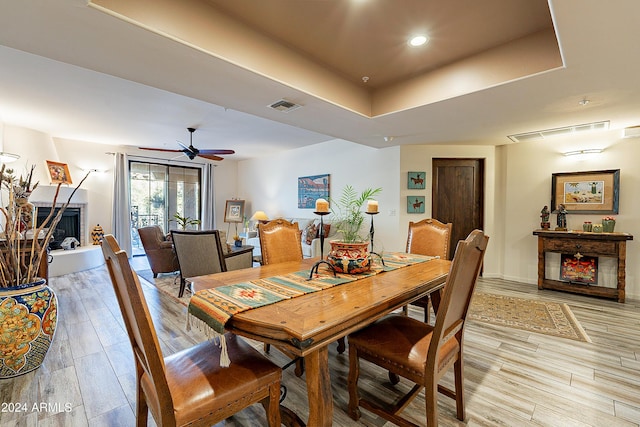 dining room featuring ceiling fan, a tray ceiling, and light hardwood / wood-style flooring