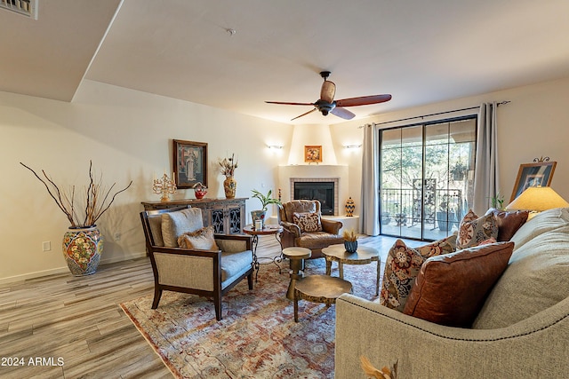 living room with a fireplace, light hardwood / wood-style flooring, and ceiling fan