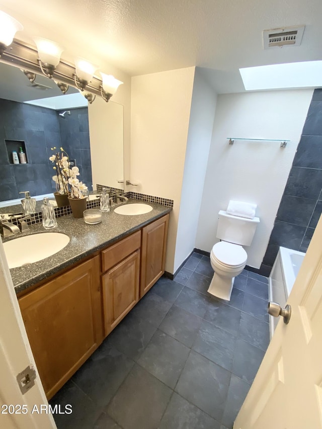 bathroom featuring toilet, a sink, visible vents, a bath, and double vanity