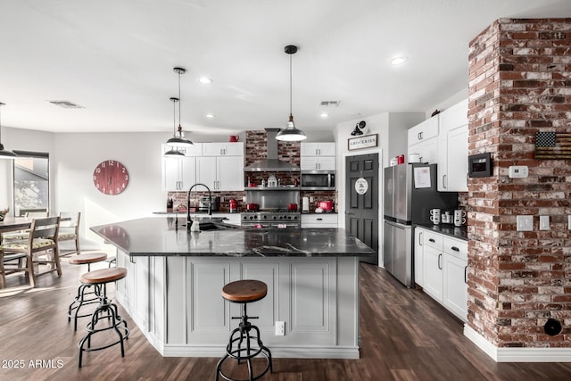 kitchen with sink, wall chimney exhaust hood, stainless steel appliances, a kitchen breakfast bar, and a spacious island