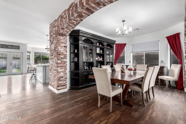 dining area with french doors, dark wood-type flooring, and a notable chandelier