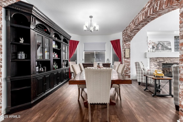 dining space with dark hardwood / wood-style flooring, a fireplace, and a chandelier